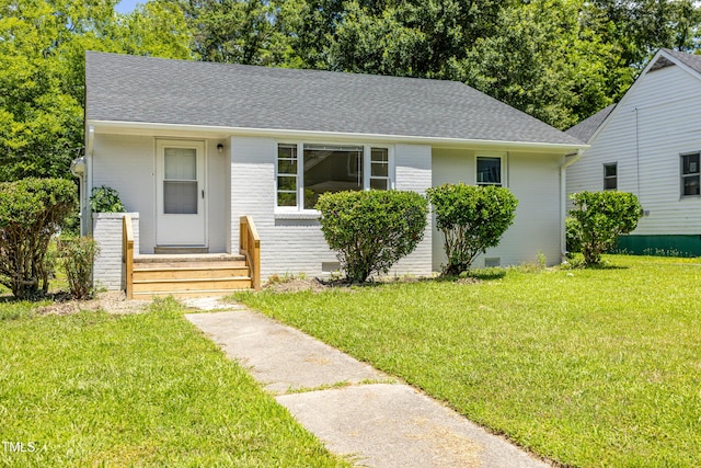 605 E Montgomery St, Henderson, NC 27536 - bungalow featuring roof with shingles, a front yard, brick siding, and crawl space