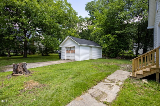 605 E Montgomery St, Henderson, NC 27536 - view of green lawn featuring an outbuilding, a detached garage, driveway, and view of wooded area