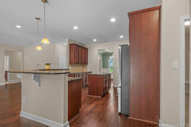 2240 Andalusian Dr, Hope Mills, NC 28348 - kitchen featuring freestanding refrigerator, a kitchen island, dark wood-style floors, dark stone counters, and recessed lighting