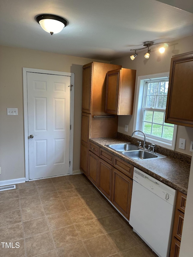 726 Thompson St, Pittsboro, NC 27312 - kitchen featuring white dishwasher, a sink, dark countertops, brown cabinetry, and baseboards