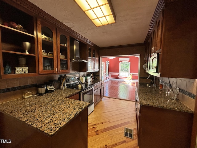 603 Hugo St, Durham, NC 27704 - kitchen with wall chimney exhaust hood, stainless steel appliances, light wood-style floors, tasteful backsplash, and dark stone countertops
