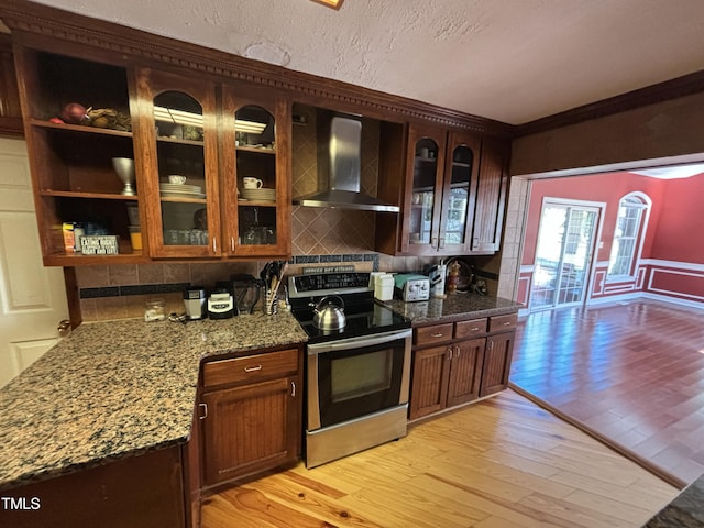 603 Hugo St, Durham, NC 27704 - kitchen featuring electric range, wall chimney range hood, light wood finished floors, backsplash, and dark stone counters