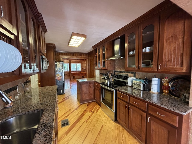 603 Hugo St, Durham, NC 27704 - kitchen with stainless steel appliances, wall chimney exhaust hood, a sink, light wood-style floors, and glass insert cabinets