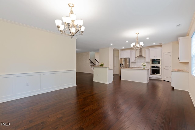 317 Springhurst Ln, Cary, NC 27511 - unfurnished living room featuring a chandelier, dark wood-type flooring, recessed lighting, stairway, and wainscoting