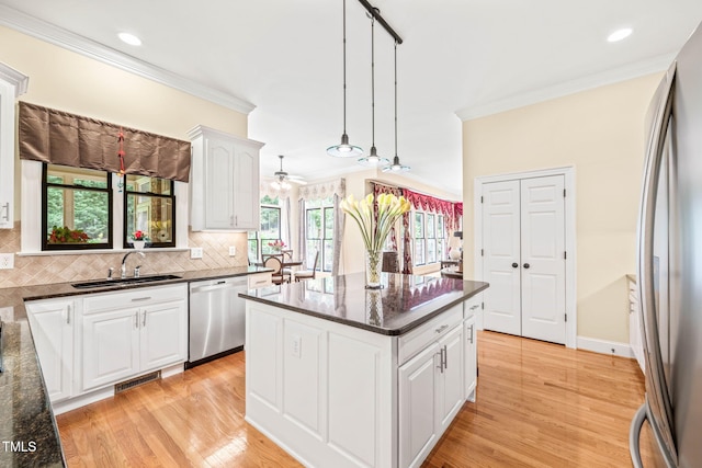 1317 Woodgate Manor Ct, Raleigh, NC 27614 - kitchen with stainless steel appliances, crown molding, tasteful backsplash, white cabinetry, and light wood finished floors