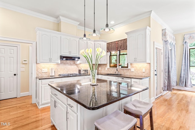 1317 Woodgate Manor Ct, Raleigh, NC 27614 - kitchen featuring appliances with stainless steel finishes, a breakfast bar area, white cabinetry, light wood-style flooring, and under cabinet range hood