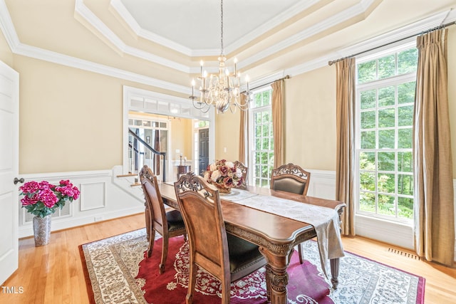 1317 Woodgate Manor Ct, Raleigh, NC 27614 - dining space featuring a tray ceiling, a chandelier, light wood-style floors, a wainscoted wall, and crown molding