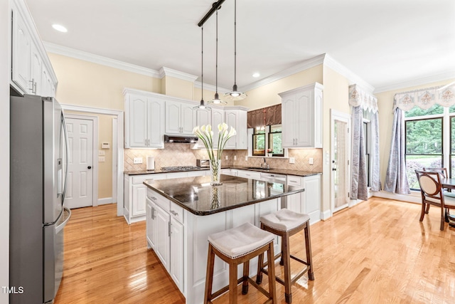 1317 Woodgate Manor Ct, Raleigh, NC 27614 - kitchen featuring stainless steel appliances, white cabinets, a breakfast bar, under cabinet range hood, and a center island