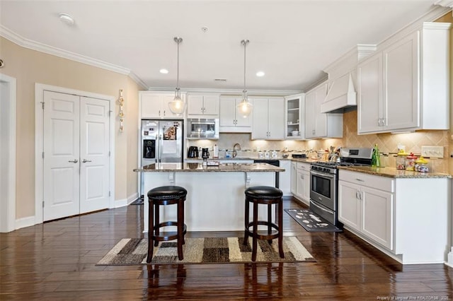 220 Hugh Shelton Loop, Fayetteville, NC 28303 - kitchen featuring appliances with stainless steel finishes, premium range hood, dark wood-style flooring, a kitchen breakfast bar, and white cabinetry