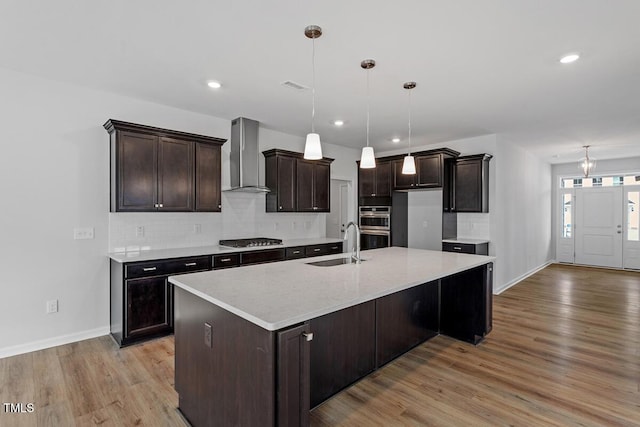 219 Berry Mill Ln Unit 179, Raleigh, NC 27603 - kitchen featuring wall chimney range hood, appliances with stainless steel finishes, light wood finished floors, tasteful backsplash, and baseboards