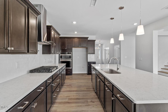 219 Berry Mill Ln Unit 179, Raleigh, NC 27603 - kitchen with a sink, appliances with stainless steel finishes, wall chimney range hood, light wood-type flooring, and dark brown cabinets