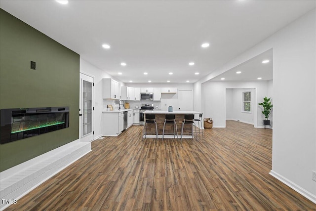 5110 Old Well St, Durham, NC 27704 - kitchen featuring appliances with stainless steel finishes, dark wood finished floors, light countertops, white cabinetry, and baseboards
