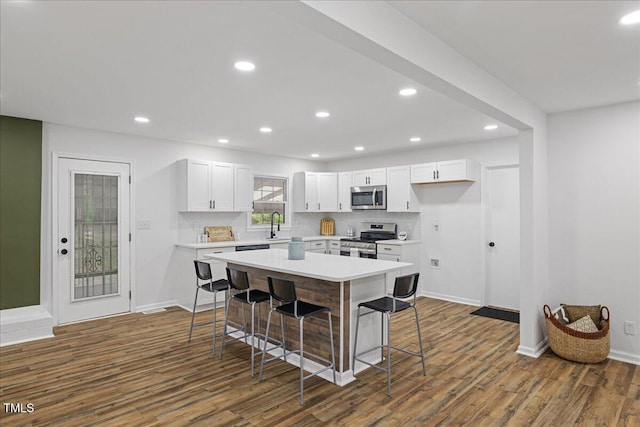 5110 Old Well St, Durham, NC 27704 - kitchen featuring appliances with stainless steel finishes, dark wood finished floors, a kitchen bar, white cabinets, and light countertops