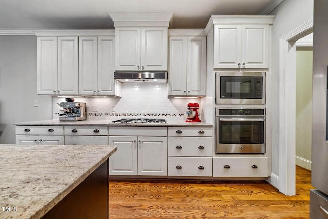 201 Margaret Mann Way, Pittsboro, NC 27312 - kitchen with stainless steel appliances, under cabinet range hood, backsplash, white cabinets, and light stone counters