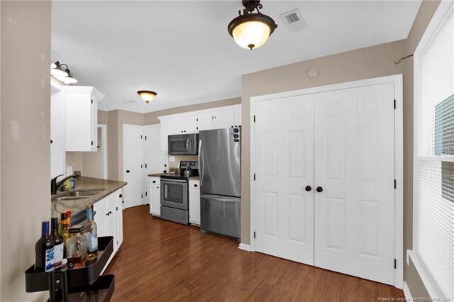 5921 Bloomsbury Dr, Fayetteville, NC 28306 - kitchen featuring stainless steel appliances, a sink, white cabinets, dark wood finished floors, and dark stone countertops