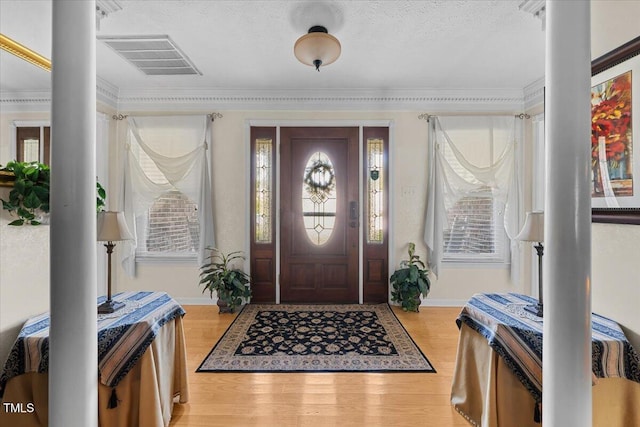 5924 Finish Line Dr, Hope Mills, NC 28348 - entrance foyer featuring decorative columns, light wood-style floors, crown molding, baseboards, and a textured ceiling
