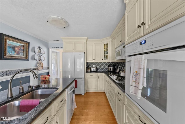 5924 Finish Line Dr, Hope Mills, NC 28348 - kitchen featuring stainless steel appliances, cream cabinetry, a sink, light wood finished floors, and glass insert cabinets
