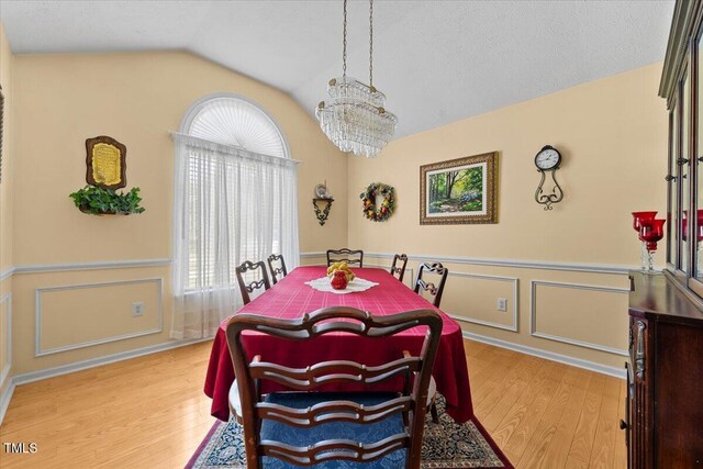 5924 Finish Line Dr, Hope Mills, NC 28348 - dining area with vaulted ceiling, light wood finished floors, a chandelier, a wainscoted wall, and a decorative wall