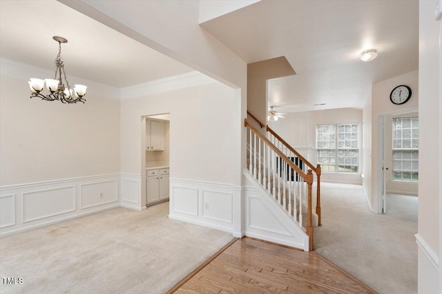 402 Halls Mill Dr, Cary, NC 27519 - stairs with a chandelier, wood finished floors, a ceiling fan, a decorative wall, and wainscoting