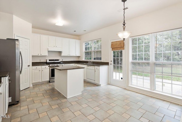 402 Halls Mill Dr, Cary, NC 27519 - kitchen with stainless steel appliances, dark countertops, under cabinet range hood, white cabinets, and a kitchen island