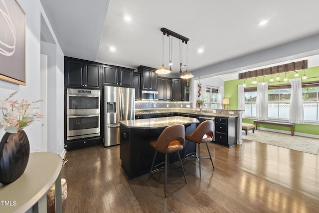 2909 Landon Pines Ct, New Hill, NC 27562 - kitchen featuring stainless steel appliances, a kitchen island, dark wood-type flooring, light stone countertops, and recessed lighting