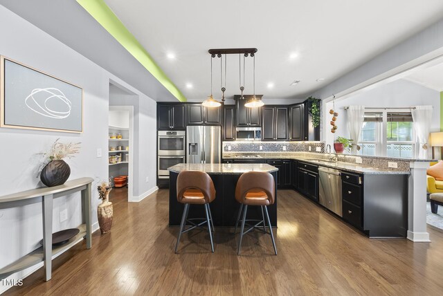 2909 Landon Pines Ct, New Hill, NC 27562 - kitchen featuring stainless steel appliances, a sink, a breakfast bar area, light stone countertops, and recessed lighting