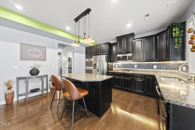 2909 Landon Pines Ct, New Hill, NC 27562 - kitchen featuring appliances with stainless steel finishes, a sink, dark cabinets, a kitchen island, and dark wood finished floors