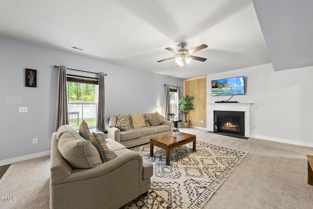 2909 Landon Pines Ct, New Hill, NC 27562 - living area featuring a fireplace with flush hearth, a ceiling fan, baseboards, and light carpet