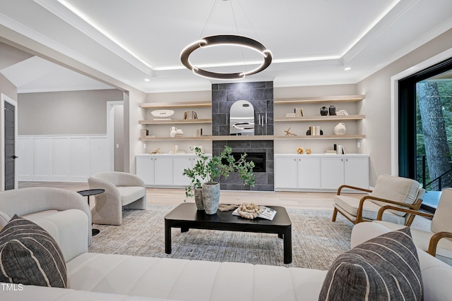 5406 Garrett Rd, Durham, NC 27707 - living area with a raised ceiling, light wood-style floors, crown molding, built in shelves, and wainscoting