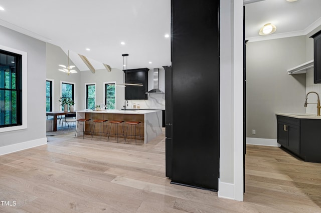 5406 Garrett Rd, Durham, NC 27707 - kitchen featuring wall chimney exhaust hood, light countertops, dark cabinetry, an island with sink, and recessed lighting