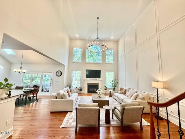 9409 Collingdale Way, Raleigh, NC 27617 - living room with a chandelier, wood finished floors, a decorative wall, a high ceiling, and a fireplace