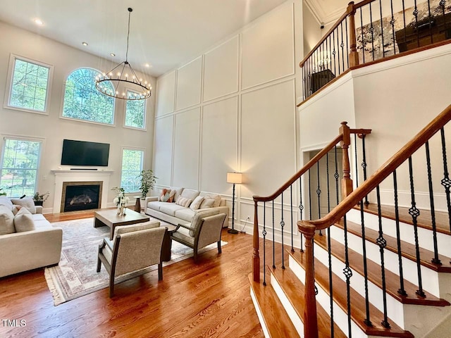 9409 Collingdale Way, Raleigh, NC 27617 - living area featuring a towering ceiling, a decorative wall, wood finished floors, a chandelier, and stairs