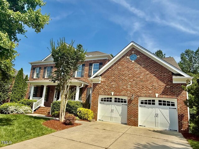 9409 Collingdale Way, Raleigh, NC 27617 - view of front facade featuring concrete driveway, brick siding, a porch, an attached garage, and a front lawn