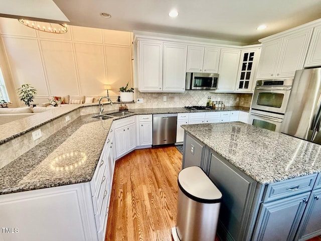 9409 Collingdale Way, Raleigh, NC 27617 - kitchen with appliances with stainless steel finishes, a sink, light wood-style flooring, white cabinets, and recessed lighting