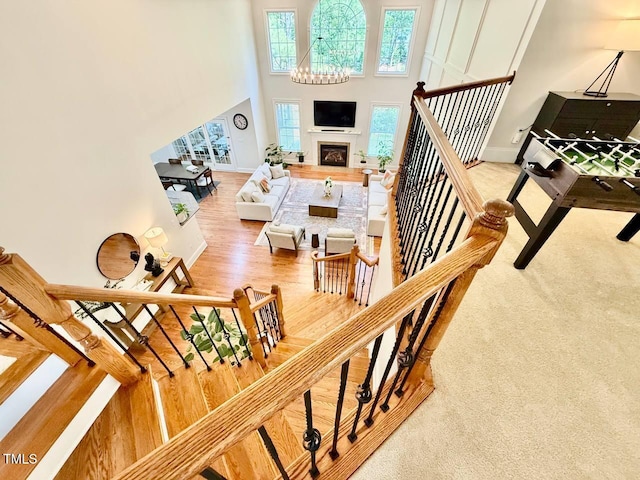 9409 Collingdale Way, Raleigh, NC 27617 - stairs featuring wood finished floors, a towering ceiling, baseboards, a fireplace, and a chandelier