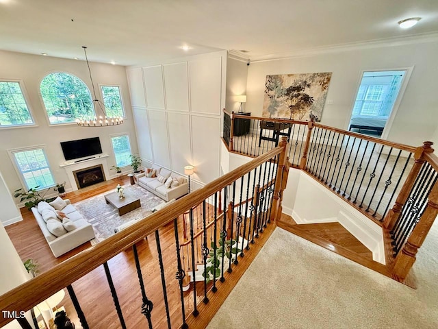 9409 Collingdale Way, Raleigh, NC 27617 - stairway featuring wood finished floors, a chandelier, recessed lighting, ornamental molding, and a fireplace with flush hearth