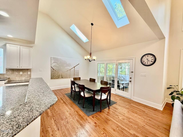 9409 Collingdale Way, Raleigh, NC 27617 - dining room with a skylight, high vaulted ceiling, a chandelier, light wood-style floors, and baseboards