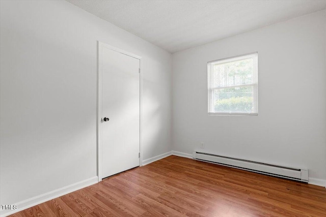 1512 Bacon St, Durham, NC 27701 - unfurnished bedroom featuring a baseboard heating unit, light wood-style flooring, and baseboards