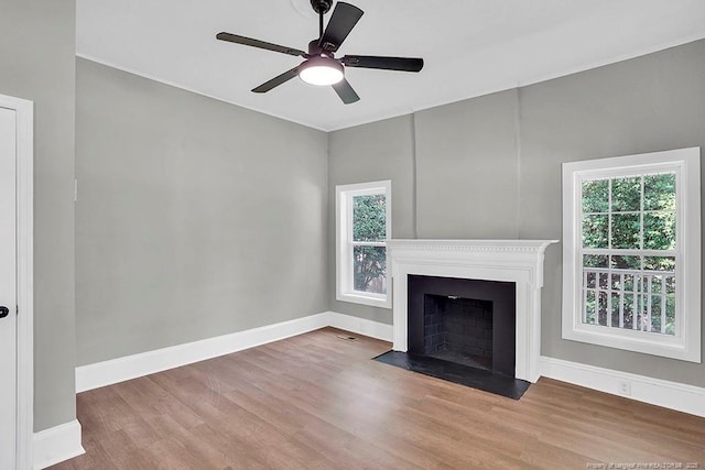 201 N College St, Red Springs, NC 28377 - unfurnished living room featuring wood finished floors, baseboards, a ceiling fan, and a fireplace with flush hearth