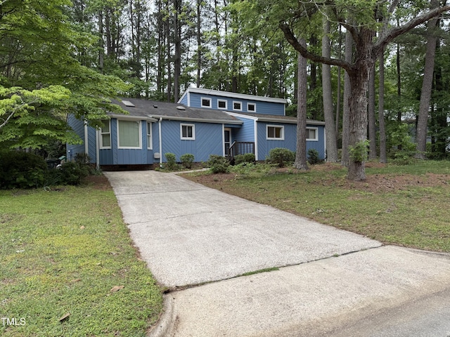 507 Holtz Ln, Cary, NC 27511 - mid-century inspired home featuring concrete driveway, a front yard, and view of scattered trees