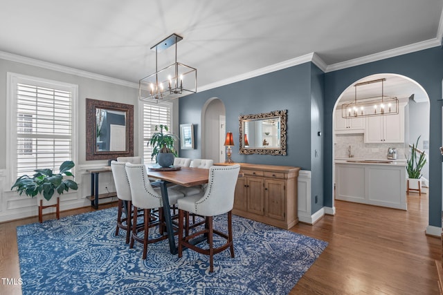 321 Commons Walk Cir, Cary, NC 27519 - dining space featuring a chandelier, arched walkways, wood finished floors, ornamental molding, and wainscoting