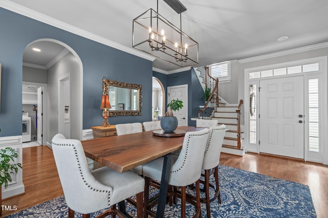 321 Commons Walk Cir, Cary, NC 27519 - dining room featuring arched walkways, stairs, a chandelier, wood finished floors, and crown molding