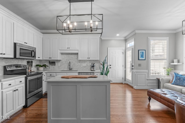 321 Commons Walk Cir, Cary, NC 27519 - kitchen with appliances with stainless steel finishes, a sink, a chandelier, ornamental molding, and white cabinetry