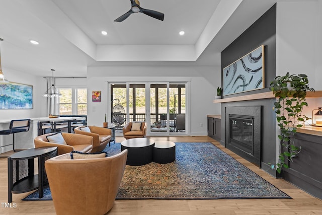 105 Scotland Dr, Youngsville, NC 27596 - living room featuring a tray ceiling, a glass covered fireplace, wood finished floors, a ceiling fan, and recessed lighting
