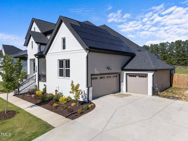 105 Scotland Dr, Youngsville, NC 27596 - view of property exterior with roof mounted solar panels, concrete driveway, brick siding, roof with shingles, and an attached garage