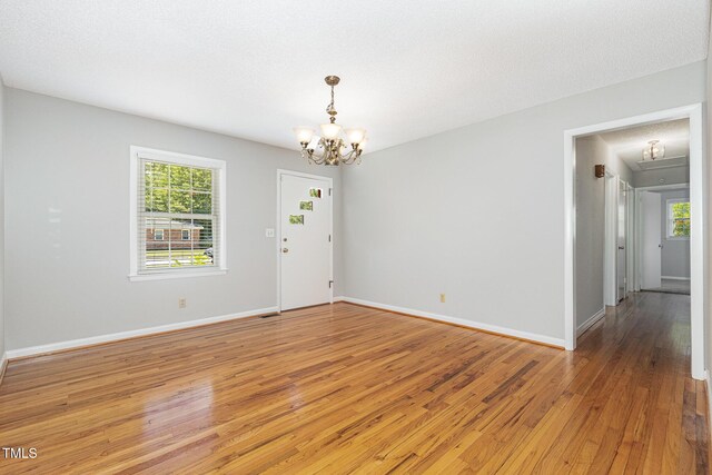 1304 Park Ave, Dunn, NC 28334 - spare room with a chandelier, light wood-type flooring, plenty of natural light, and baseboards