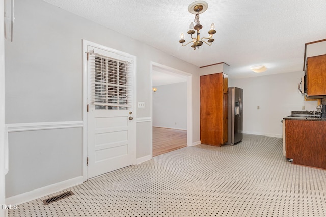 1304 Park Ave, Dunn, NC 28334 - kitchen featuring appliances with stainless steel finishes, brown cabinets, dark countertops, a chandelier, and a textured ceiling