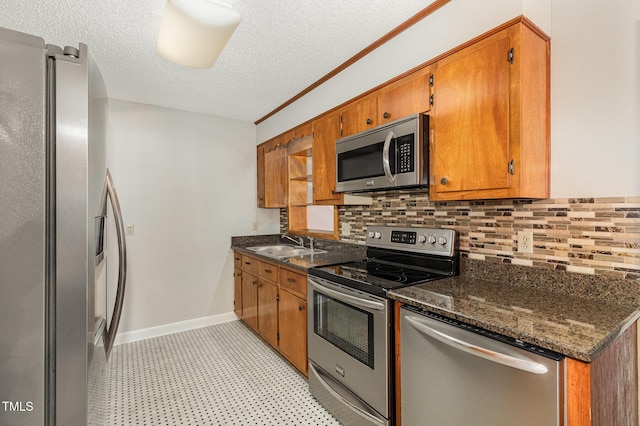 1304 Park Ave, Dunn, NC 28334 - kitchen with stainless steel appliances, decorative backsplash, a sink, brown cabinetry, and a textured ceiling
