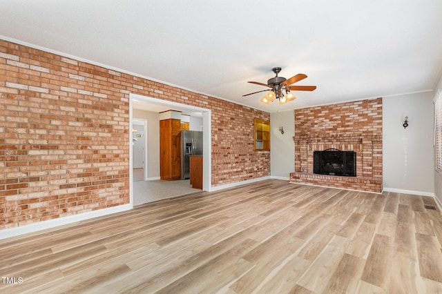1304 Park Ave, Dunn, NC 28334 - unfurnished living room with a ceiling fan, baseboards, brick wall, light wood-style floors, and a brick fireplace