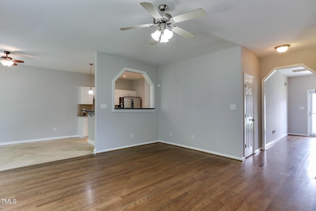 1310 Southgate Dr, Raleigh, NC 27610 - unfurnished living room featuring ceiling fan, arched walkways, wood finished floors, and baseboards